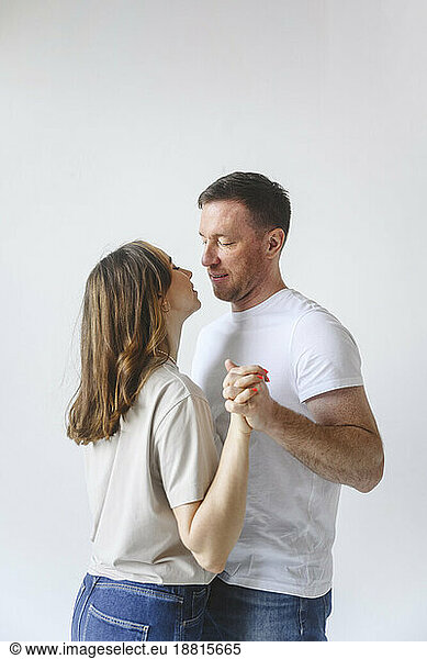 Romantic couple dancing against white background