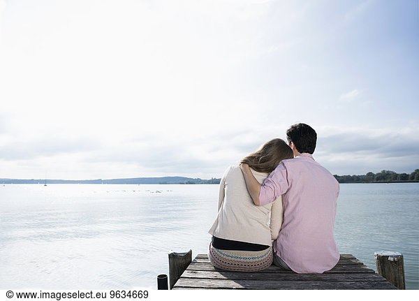 Romantic couple hugging lake jetty tranquil