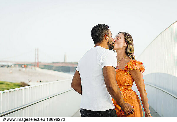 Romantic couple kissing each other on footpath