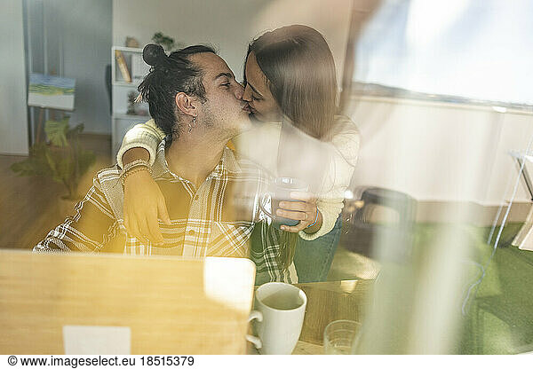 Romantic couple kissing on mouth seen through glass