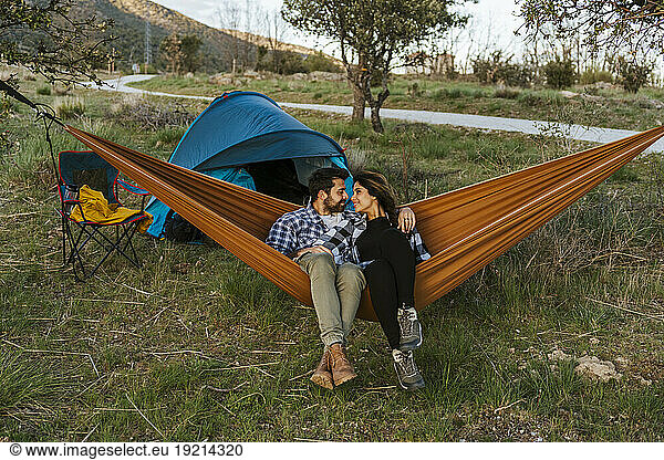 Romantic couple sitting in hammock near tent