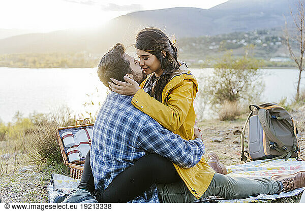 Romantic couple sitting on picnic blanket in front of mountain