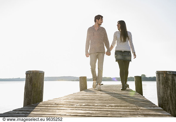 Romantic couple walking wooden jetty lake