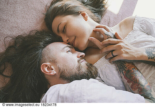Romantic hipster couple lying on bed at home