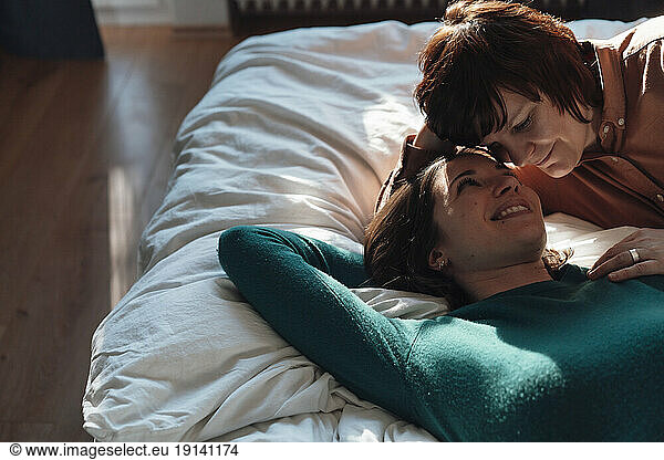 Romantic lesbian couple spending leisure time on bed at home