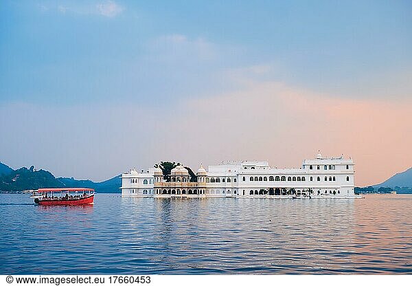 Romantic luxury India travel tourism  tourist boat in front of Lake Palace (Jag Niwas) complex on Lake Pichola on sunset with dramatic sky  Udaipur  Rajasthan  India