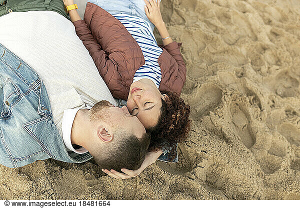 Romantic man and woman lying with eyes closed on sand at beach