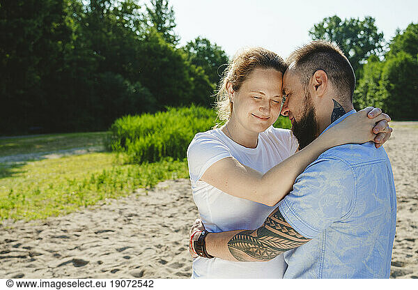 Romantic man embracing pregnant woman on field