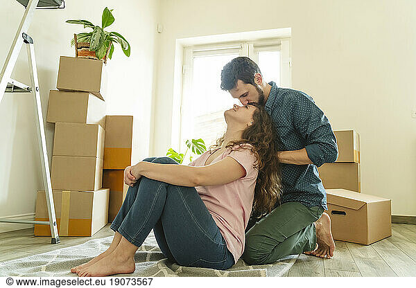 Romantic man kneeling and kissing girlfriend at new home