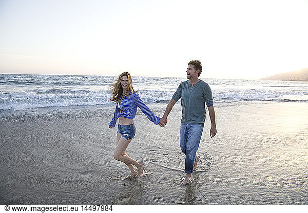 Romantic Mid-Adult Couple Holding Hands While Walking Along Beach