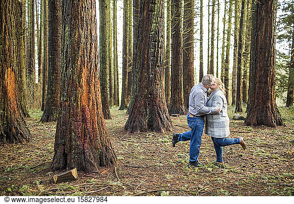 Romantic retired couple kissing in the woods.