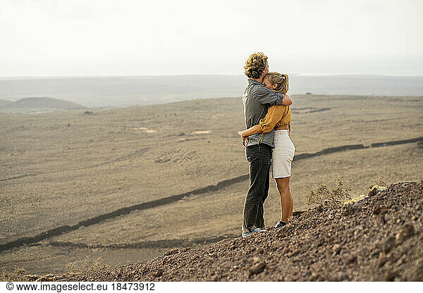 Romantic young couple embracing each other standing on mountain