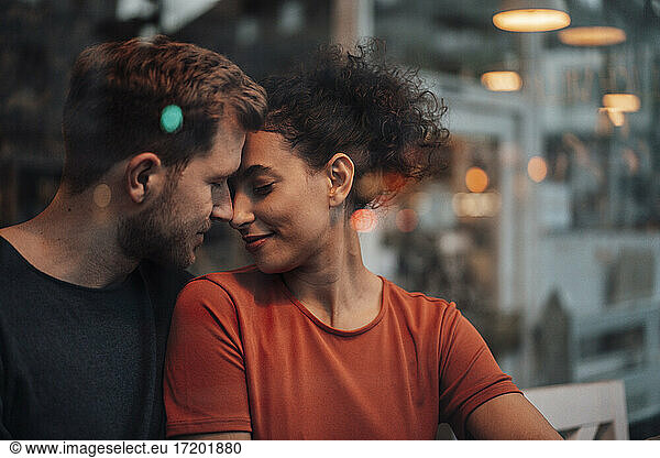 Romantisches Paar mit geschlossenen Augen sitzt sich im Café gegenüber