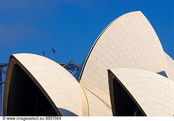 Roof of Sydney Opera House framed against the peak of the Sydney Harbour Bridge.