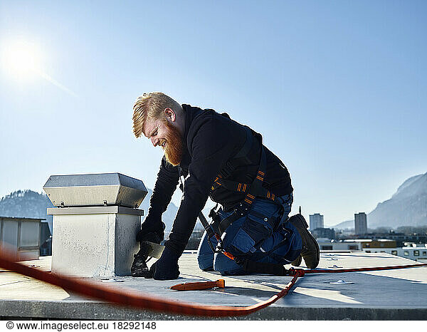 Roofer repairing roof on sunny day