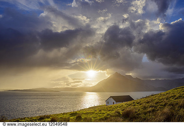 Rooftop of a house along the Scottish coast with sun shining through the clouds over Loch Scavaig  Isle of Skye in Scotland