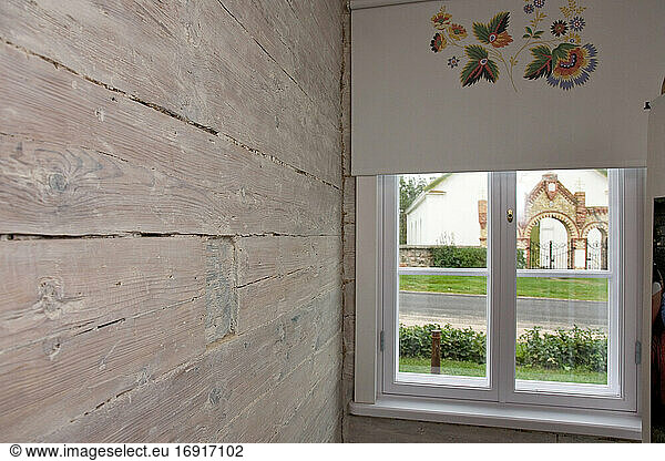 Room with wooden wall and window and patterned window blind.