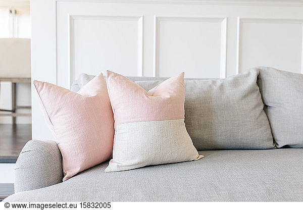 Rosa Kissen auf einer grauen Couch