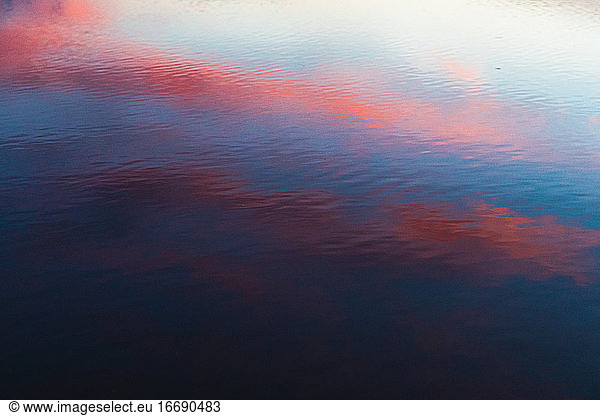 rosa orange und blau Kontrast Reflexion des Sonnenuntergangs auf gekräuselten Wasser