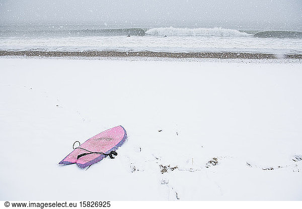 Rosa Surfbrett am schneebedeckten Strand