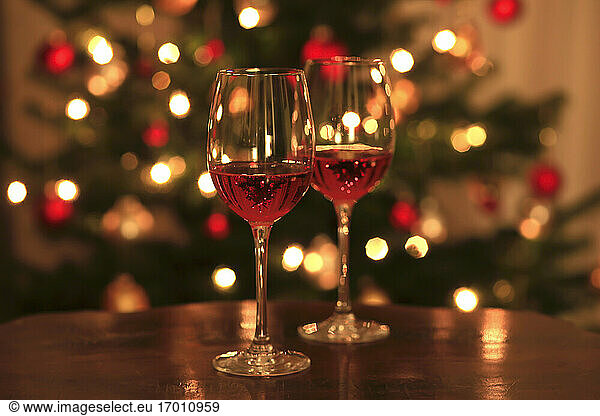 Rose wine in shiny wineglass in front of Christmas tree
