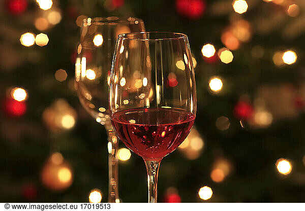 Rosenwein in glänzenden Weingläsern vor dem Weihnachtsbaum