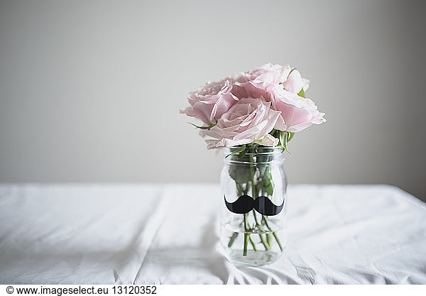 Roses in glass jar on table at home