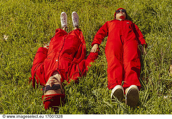 Rot gekleidetes junges Paar auf einer Wiese im Sonnenlicht liegend