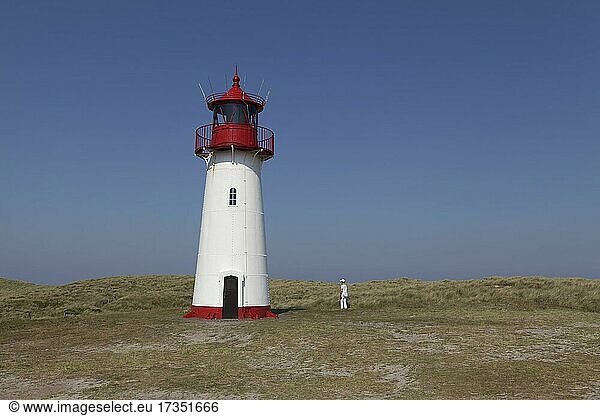 Rot-weißer Leuchtturm List-West  davor einzelne Touristin  weiß gekleidet  Ellenbogen  Sylt  Ostfriesische Inseln  Schleswig-Holstein  Deutschland  Europa