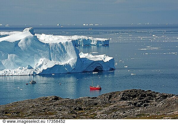 Rotes Fischerboot in einer Bucht mit riesigen Eisbergen  weite Bucht mit Eisbergen dahinter Bucht mit Eisbergen  Ilulissat  Arktis  Nordamerika  Grönland  Dänemark  Nordamerika