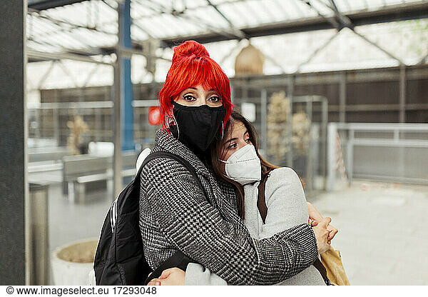 Rothaarige Frau umarmt Freundin am Bahnhof