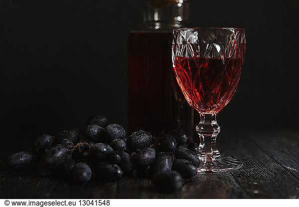 Rotwein und Trauben vor schwarzem Hintergrund