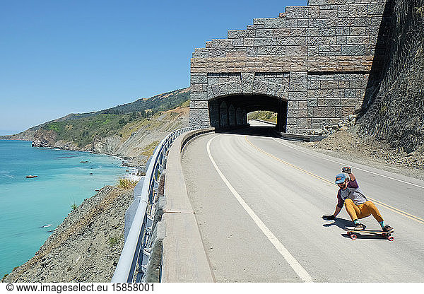 Route One in Big Sur with Man Skateboarding  Ocean and Cliff in Back