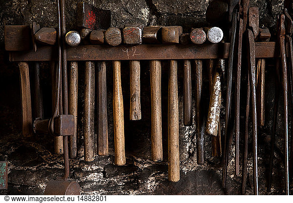 Row of blacksmiths hammers and tongs on workshop wall