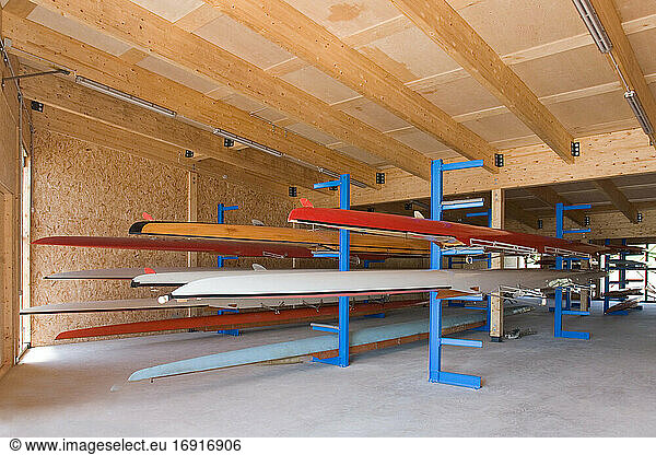 Rowing sculls or boats stored on rack in boathouse.