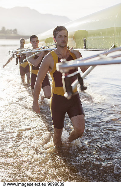 Rowing team carrying scull in lake
