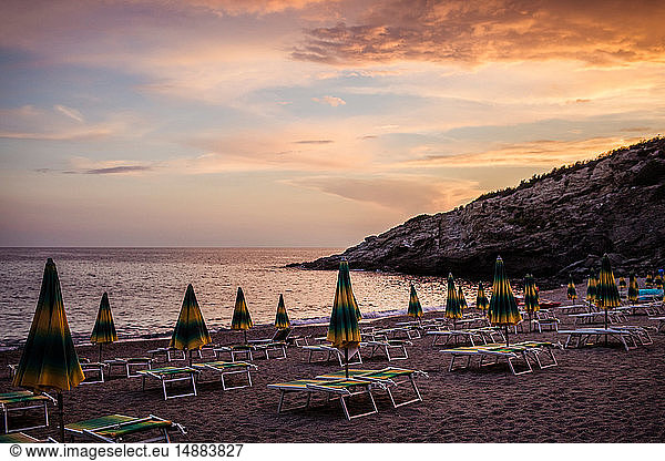 Rows of empty sun loungers and parasols on beach at sunset  Capoliveri  Tuscany  Italy