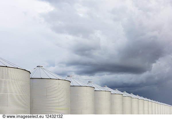 Rows of grain silos  stormy skies in distance  Saskatchewan  Canada.