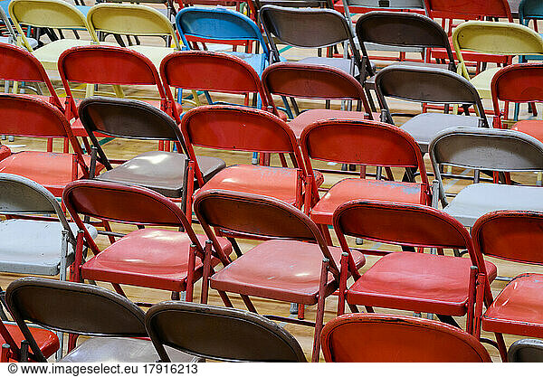 Rows of metal folding chairs of different colours  grey  red  yellow.