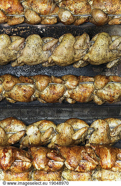 Rows of roasted chickens on a rotisserie  San Francisco  California.