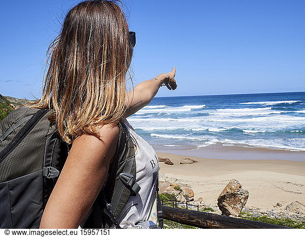 Rucksackfrau  die mit dem Finger auf den Ozean zeigt  Robberg Nature Reserve  Südafrika