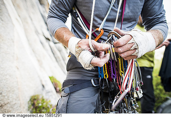 Rugged climber hands sorting through climbing gear