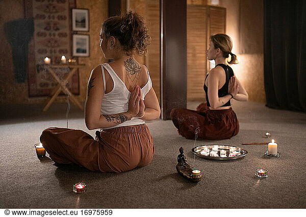 Ruhig meditierende Freundinnen bei Kerzen und Weihrauch