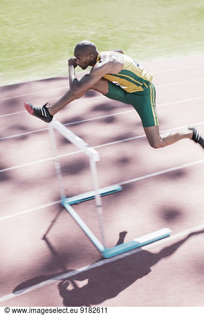 Runner clearing hurdle on track