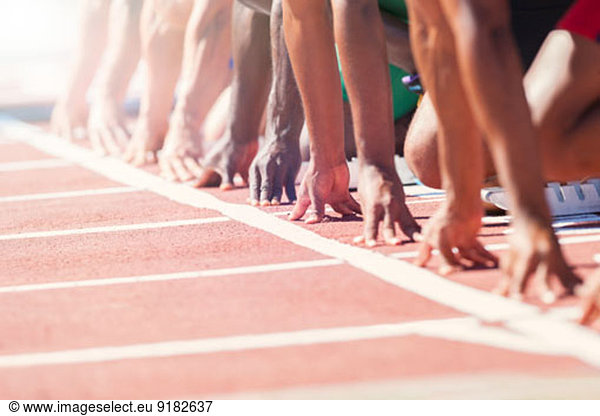 Runners poised at starting blocks on track
