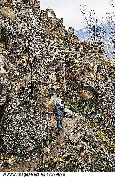 Russia, Dagestan, Gamsutl, Female tourist exploring old abandoned mountain village in North Caucasus