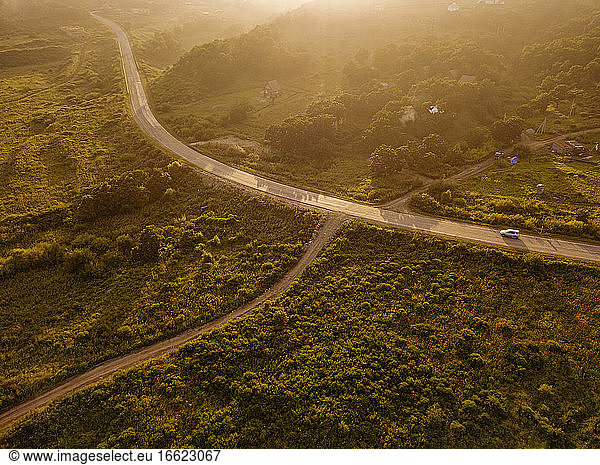 Russia  Primorsky Krai  Zarubino  Aerial view of car driving along rural road at sunset