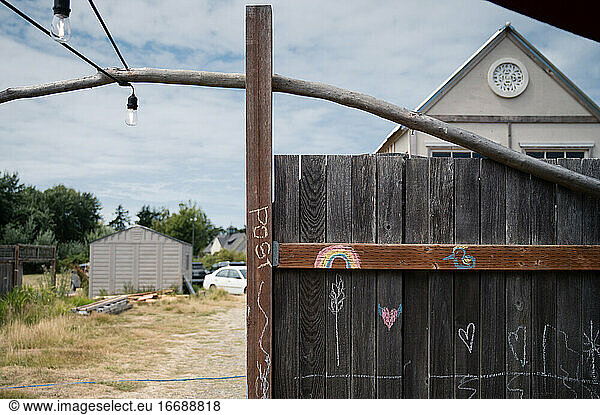 Rustic Fence with Chalk Drawings With Outdoor Structures and Building Materials in Background