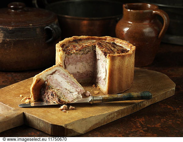 Rustic still life with layered pork  chicken and stuffing pie on chopping board