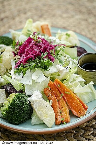 Rustikaler Hüttensalat mit gesundem gemischtem gedünstetem und frischem Gemüse auf buntem Teller.